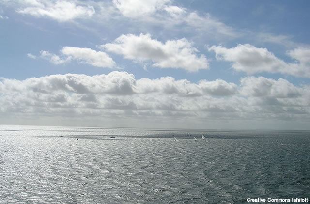 photo of sea and sky on a day with cumulus cloud present