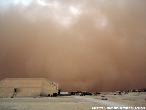 A strong sandstorm approaches the hangars at this desert airport.